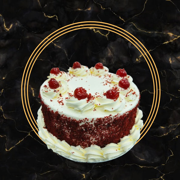 Classic red velvet cake topped with cherries and cream cheese frosting on a black marble background