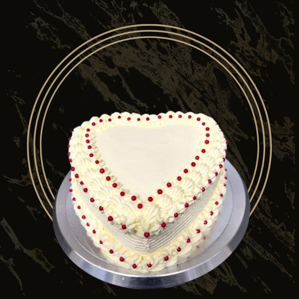 Elegant Heart-shaped white cake with smooth vanilla frosting, minimal floral décor, and refined finish from The Bakers Shop in Birmingham