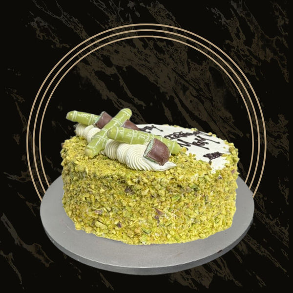 Pistachio cake topped with crushed pistachios, cream swirls, and golden flakes from The Bakers Shop in Birmingham